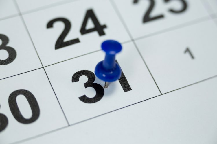Blue pin push on day 31st of month end on white calendar