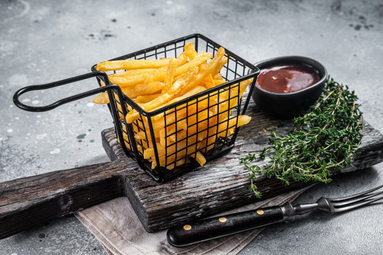 Fried French fries potatoes with salt in basket..