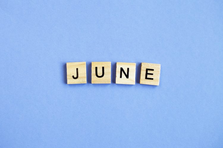 inscription June made by wooden cubes on a veri peri purple background.