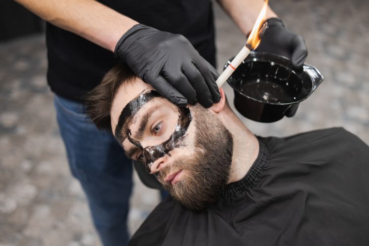 Man in a beauty salon is removing earwax using candles. Male enjoying a spa treatment