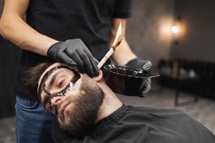 Man in a beauty salon is removing earwax using candles. Male enjoying a spa treatment