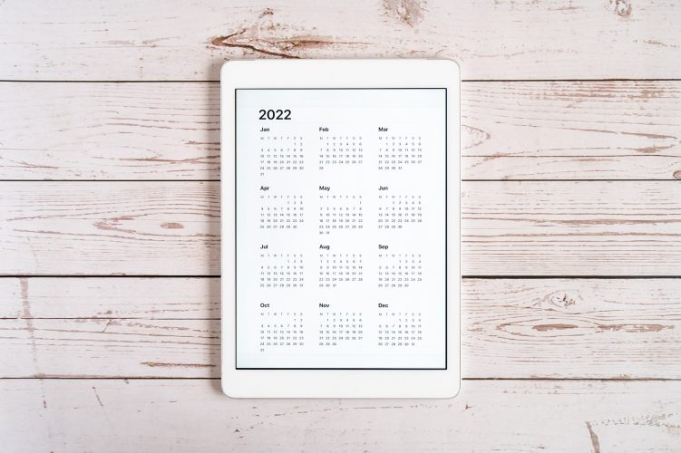 tablet computer with open calendar for 2022 year on wooden table. to do list goals flat lay