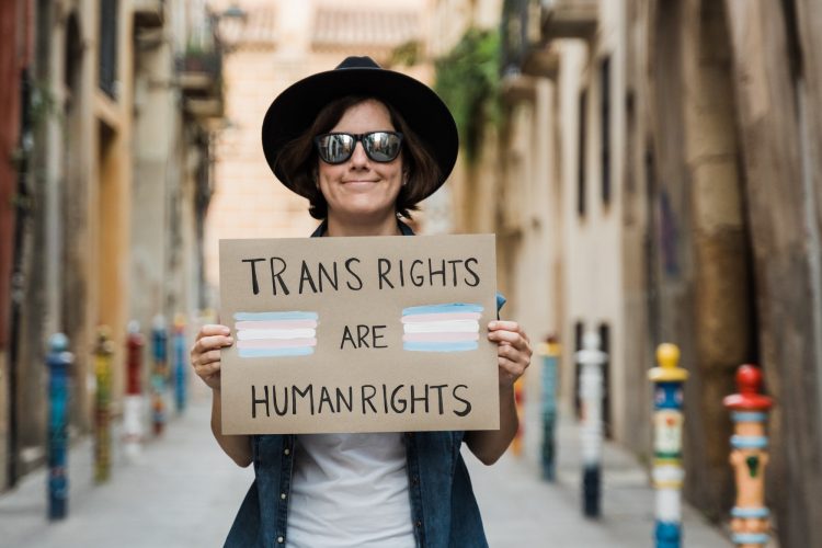 Transgender hipster woman fighting for transsexual human rights at gay pride holding banner