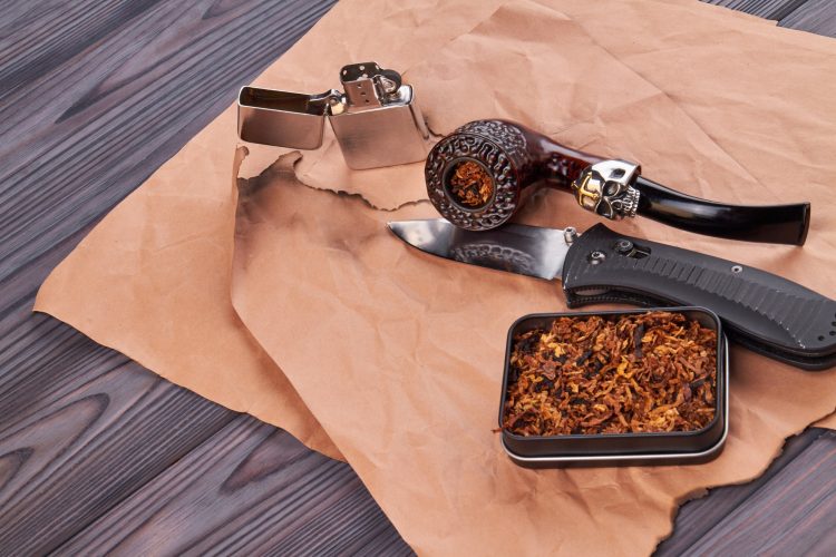 Compoistion of smoking pipe with tobacco and lighter.