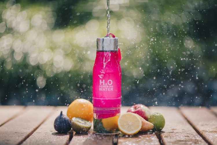 Drink more water bottle with fruits under water drops
