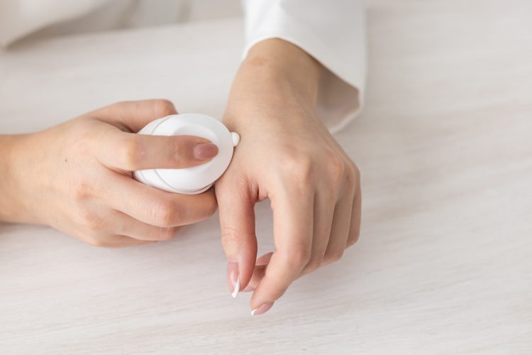 Female hands with cream. Woman applies cream on her hands. Palms down with smooth skin on hands