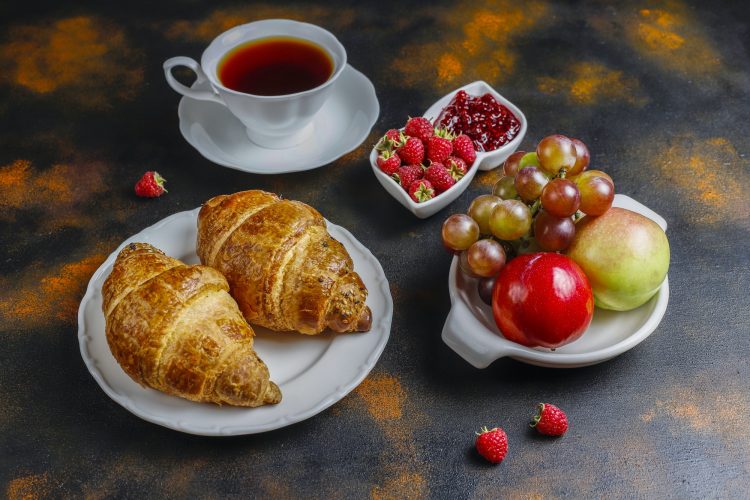 Freshly baked croissants with raspberry jam and raspberry fruits.