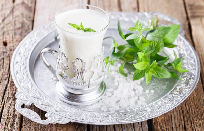 Glass of buttermilk and a bunch of mint on the tray.Milk product.