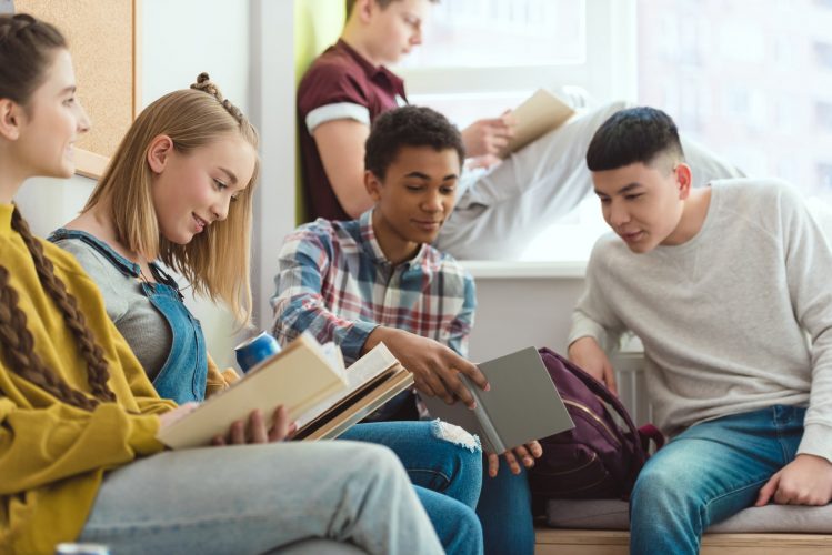 Group of multicultural high school teenage high school students doing homework during school break