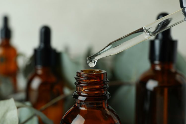 Pipette with drop of eucalyptus oil dripping over the bottle