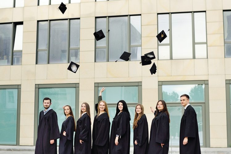 students in robes throw up academic caps and are happy to receive higher education