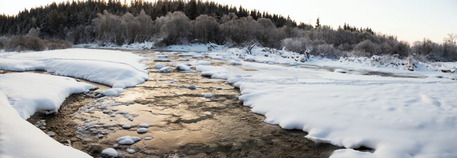 Water flowing between ice and snow in a river in winter
