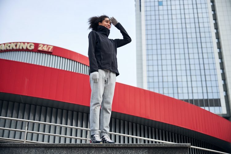 Woman standing straight and shielding her eyes with a palm