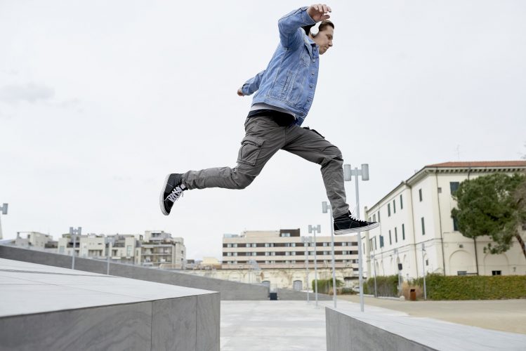 Young man jumping over gap between walls, mid air