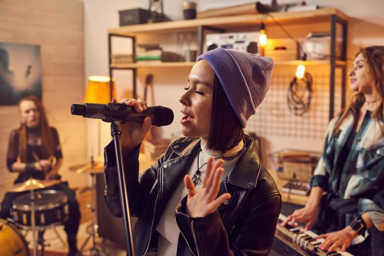 Young pretty female musician recording songs