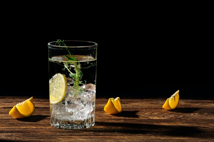 Carbonated cold water with ice and lemon casting a shadow