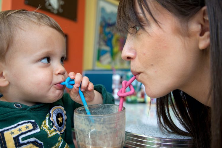 Mother and baby son using curly straws