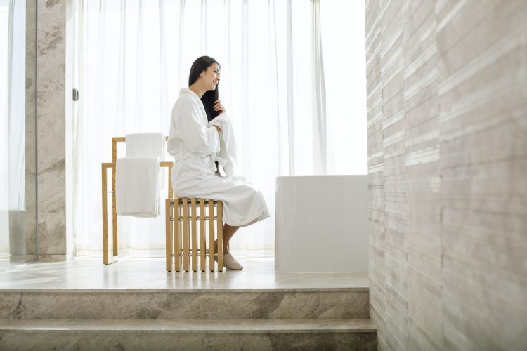 Young woman drying her hair with a towel in bathroom