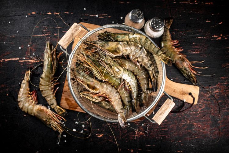 Fresh uncooked shrimp in a colander.