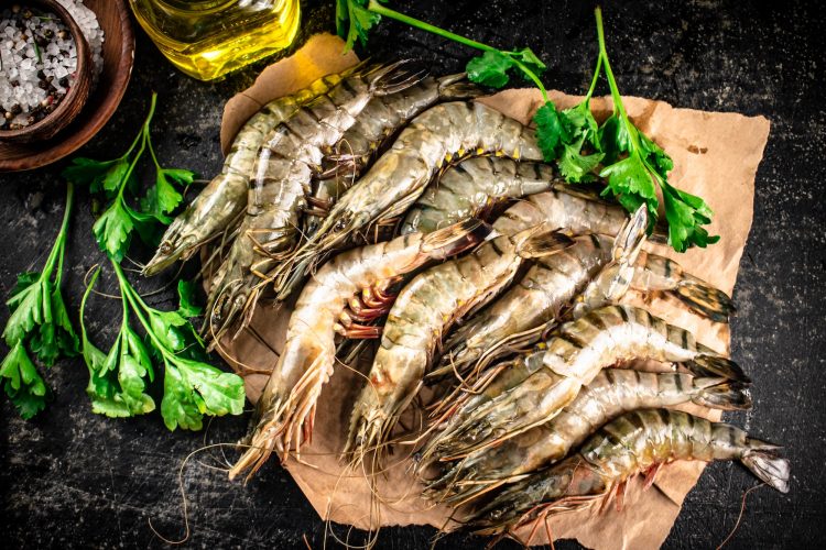 Raw shrimp on paper with spices and parsley.