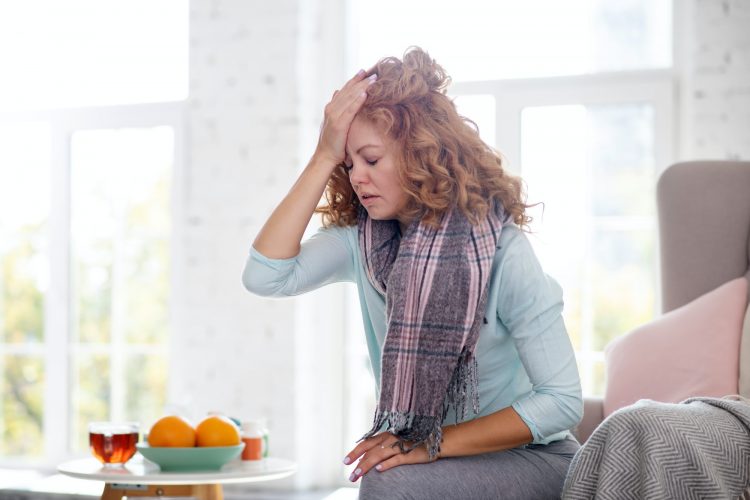 Woman touching her forehead while feeling dizzy having flu