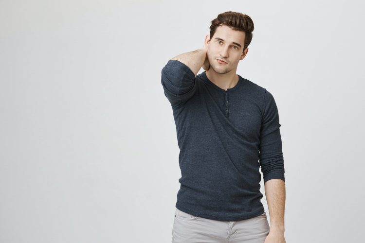 Portrait of slim handsome man scratching his neck and looking at camera feeling unconfident