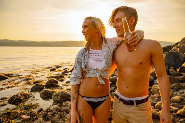 Smiling Scandinavian Couple Standing At Beach Against Sky