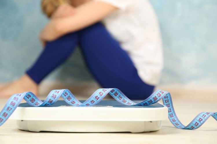 Woman is sad. Scales with measuring tape. Weight gain