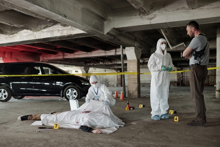 Young policeman communicating with forensic expert at crime scene
