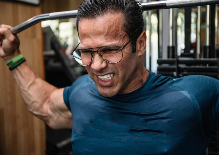 Detail of the face of a man doing strength with glasses doing bodybuilding exercises