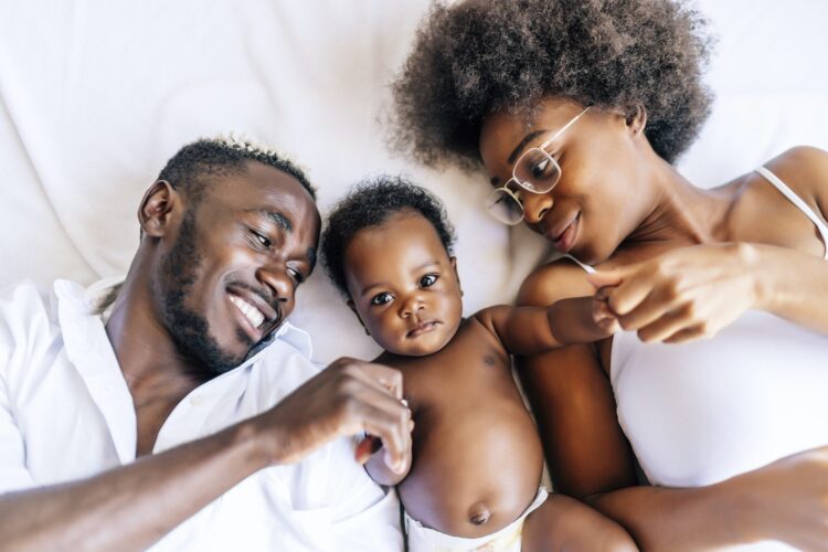 Cheerful family of African-Americans with a mother, father and baby having fun together