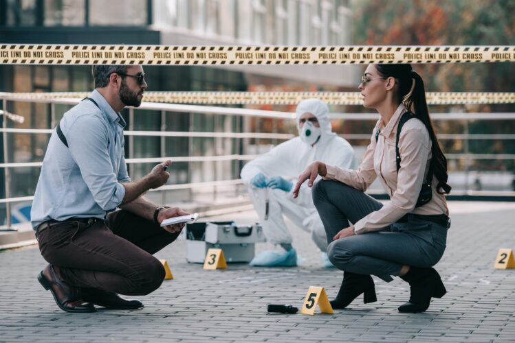 female and male detectives in sunglasses share their opinions at crime scene