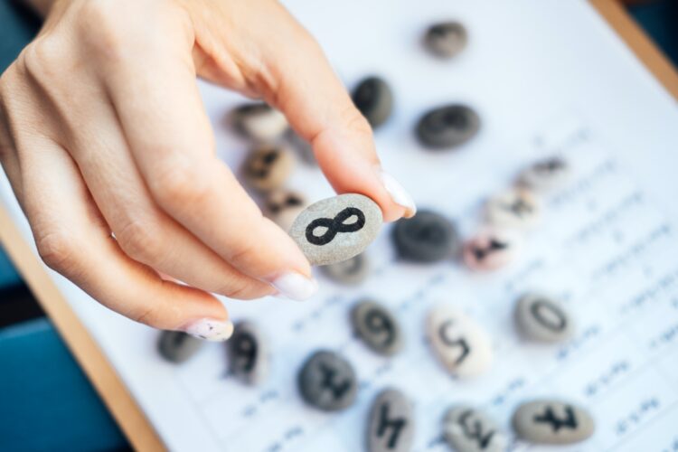Woman numerologist hand with pebble stone with Infinity symbol