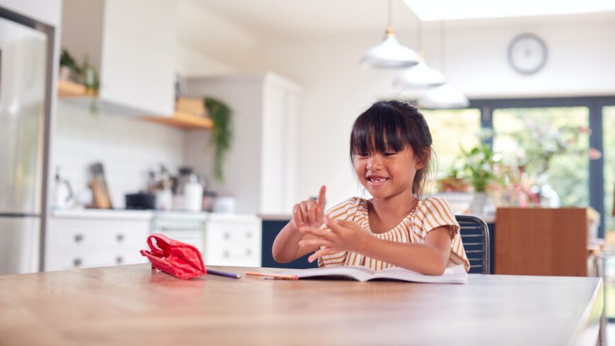 Young Asian Girl Home Schooling Working At Table In Kitchen Counting On Fingers