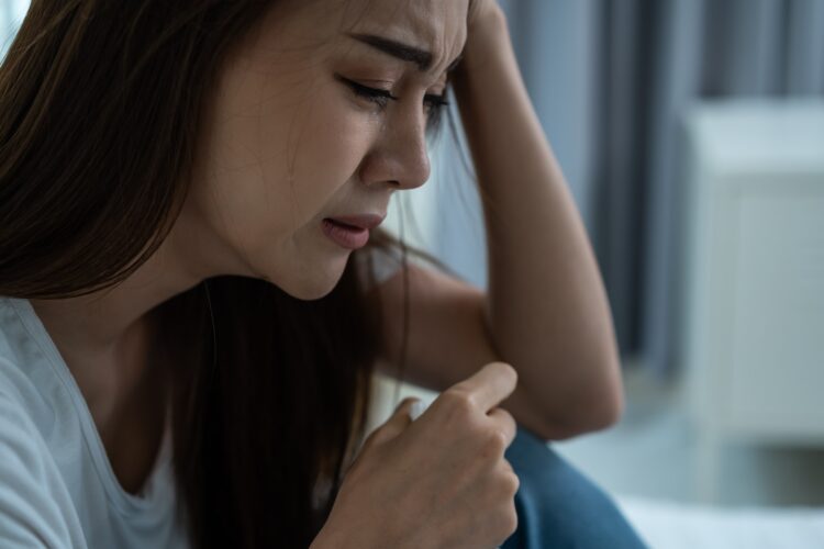 Asian beautiful depression girl crying in tears sit on bed in bedroom.