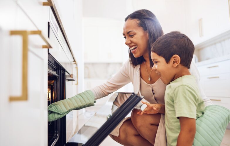 Mother, child and baking in oven learning to make biscuits, cookies or cake in home kitchen. Care,