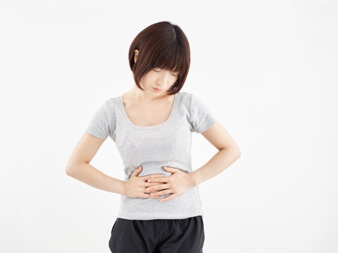Woman holding a sore belly against a white background