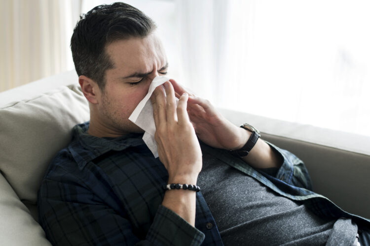 A sneezing Caucasian man on sofa