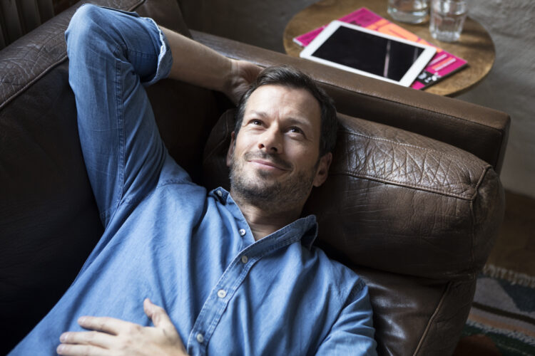 Man lying on couch, daydreaming