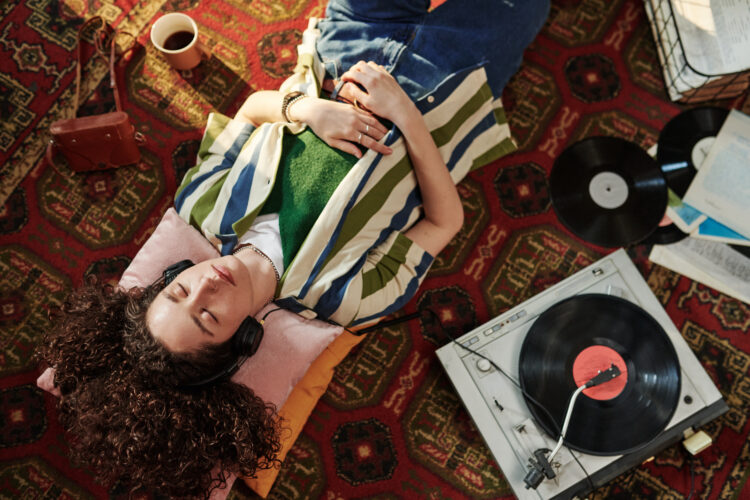 Above angle of young female in casualwear enjoying music in headphones