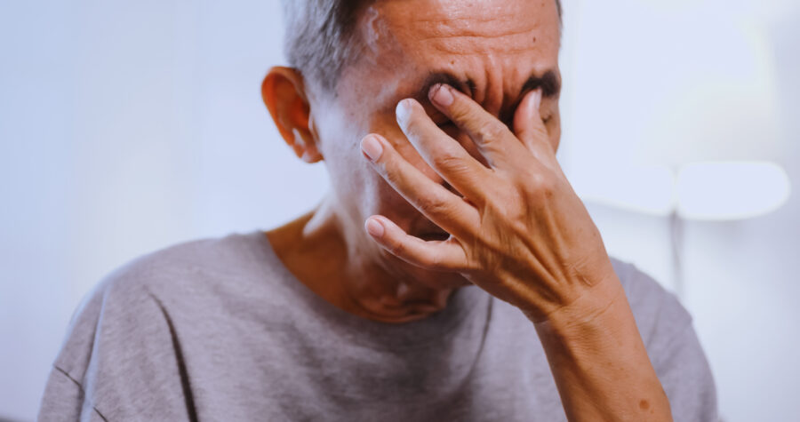 An elderly Asian man has blurred vision from staring at his phone for a long time.