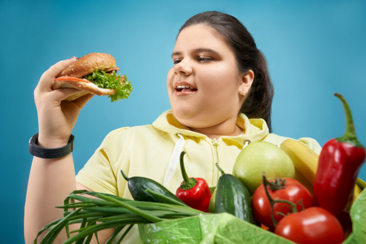 Portrait of overweight girl that pretending to eat burger