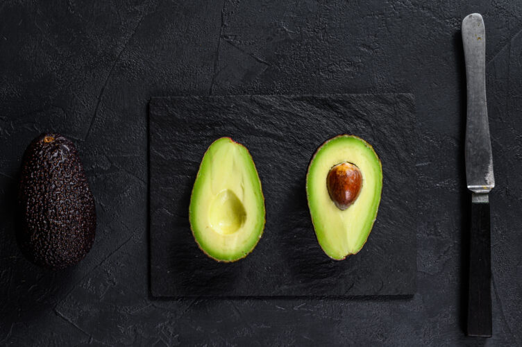 Sliced ripe avocado. Black background. Top view