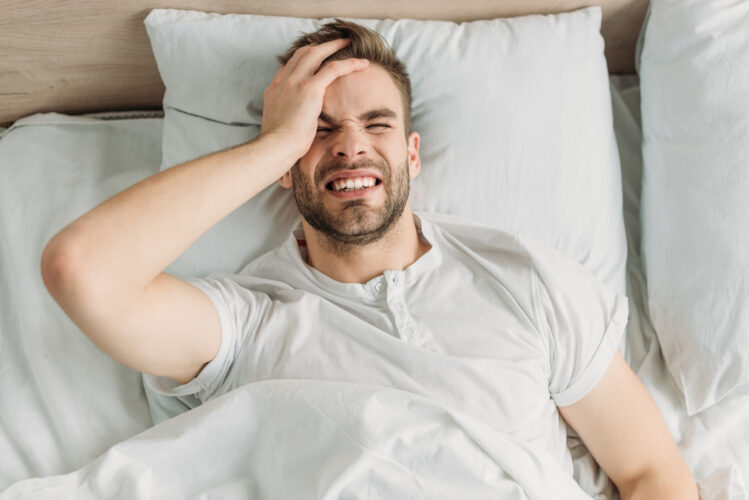 top view of young man touching head while suffering from migraine