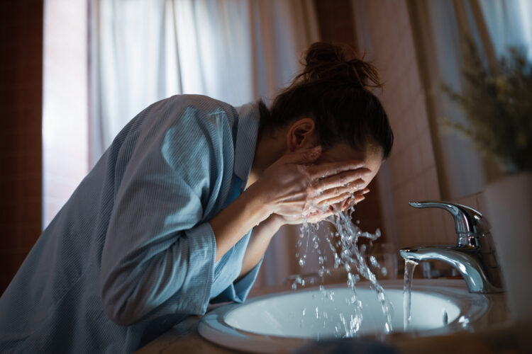 Woman washing her face in the bathroom.