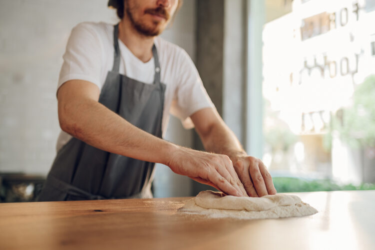 Kitchen chef preparing dough for pizza while working in a pizza place