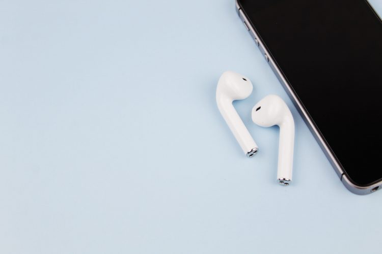 AirPods earphones with smartphone on a blue background