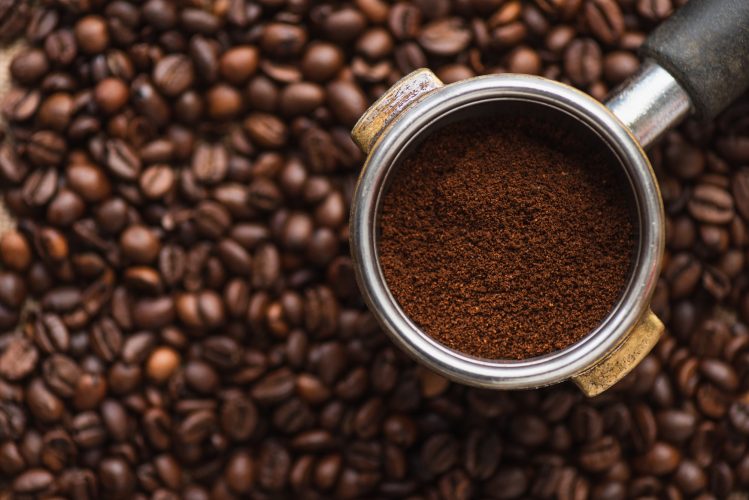 top view of ground coffee in portafilter on coffee beans background