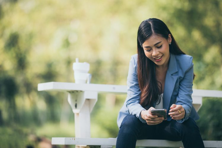 Asian business women are using smartphones to contact customers in the garden.