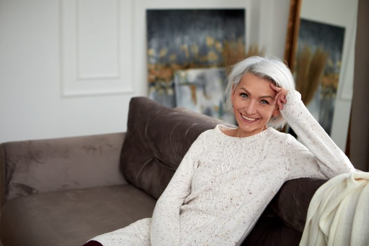 Stylish woman with gray hair on couch